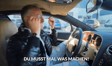 a man sitting in a car with du musst mal was machen written on the screen