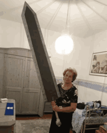 a woman is holding a very large sword in a bedroom