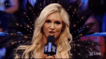 a blonde woman is speaking into a microphone with a wwe logo on it