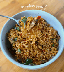 a bowl of noodles is being eaten with a fork and says " มา ม่า " on the bottom