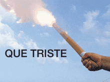 a person holding a torch with que triste written on the bottom