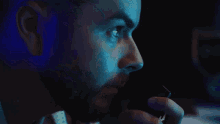 a man with a beard is talking on a phone in a dark room