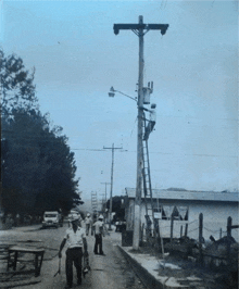 a black and white photo of a man carrying a ladder