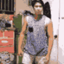 a man is standing in front of a door wearing a blue tank top and white shorts .