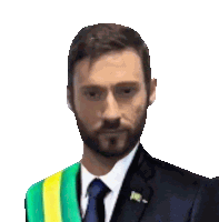 a man with a beard is wearing a suit and tie with a green and yellow sash around his neck