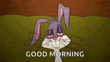 bugs bunny is laying on a couch with his eyes closed and the words `` good morning '' written above him .