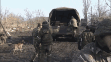 a group of soldiers are standing in front of a truck with a dog and a caption that says ojklkdg