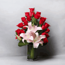 a vase filled with red roses and pink lilys