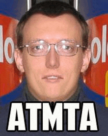 a man wearing glasses and a blue shirt is standing in front of a red sign that says atmta .