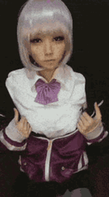 a woman wearing a purple jacket and a white shirt with a purple bow is making a funny face .