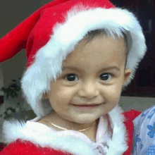 a little girl is wearing a santa hat and smiling at the camera