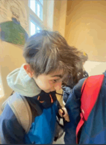 a boy wearing a blue jacket has a red backpack