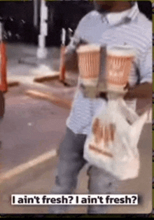 a man is carrying two cups and a bag and says i ain 't fresh