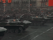 a group of military vehicles are driving down a street in front of a sign that says ' a '