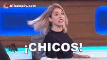 a woman sitting at a table with the words chicos written on it