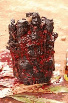 a statue covered in blood is sitting on a table next to a bottle of blood .