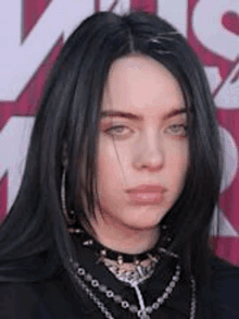 billie eilish is wearing a choker necklace and earrings .