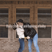 a couple kissing in front of a brick building with the words holy crap we are having a baby below them