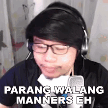 a man wearing headphones and glasses is talking into a microphone and says parang walang manners eh .