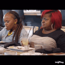 a woman with red hair is sitting at a table with a plate of food and a glass of water