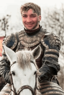 a man in armor is riding a horse and smiling .