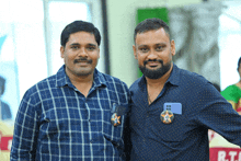 two men are posing for a picture and one has a badge that says rt