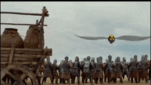 a group of soldiers standing in front of a cart with a bird flying in the sky