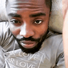 a man with a beard and a t-shirt that says `` for love and love '' is laying on a couch .