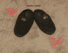 a pair of black slippers on a carpet with daddy 's home written above them