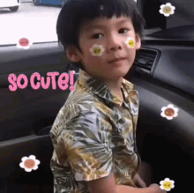 a young boy is sitting in the driver 's seat of a car with stickers on his face and the words so cute behind him .