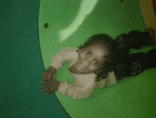 a little girl is laying on a green circle and smiling