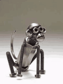 a metal monkey made out of nuts and bolts is sitting on a white surface .