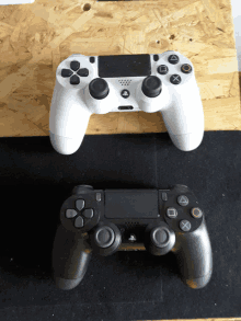 a white playstation controller is next to a black playstation controller