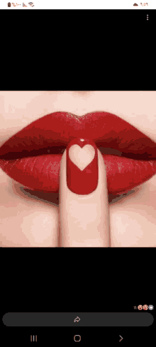 a close up of a woman 's lips with red lipstick and a heart on her nail