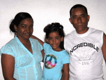 a man , a woman and a little girl are posing for a picture .