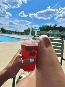 a woman is holding a red drink with a straw