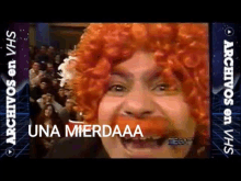 a man with a red wig says una mierdaaa in front of a crowd of people