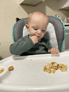 a baby is sitting in a high chair eating a snack