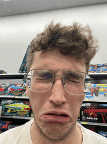 a man wearing glasses is making a funny face in front of a nerf fortnite toy