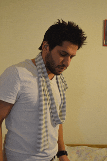 a man with a scarf around his neck looks down at something