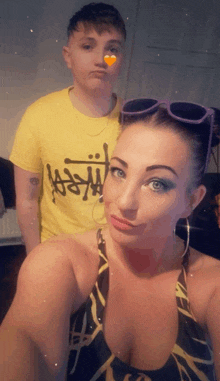 a man in a yellow stussy shirt stands next to a woman in a swimsuit