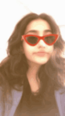 a woman wearing red heart shaped sunglasses looks at the camera .