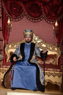 a man in a blue and black costume is sitting on a couch with a cane