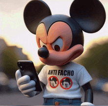 a statue of mickey mouse wearing an anti facho t-shirt holds a cell phone