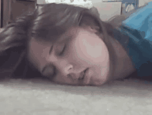 a young woman is laying on the floor with her eyes closed .