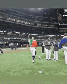 a group of people are standing on a baseball field with a sign that says ' t ' on it