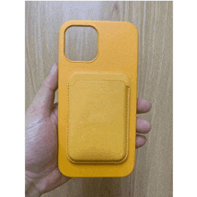 a person is holding a yellow iphone case with a pocket