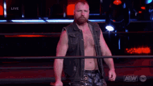 a man in a leather vest is holding a championship belt in a wrestling ring ..