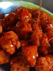 a bowl of fried chicken with sauce being poured over it