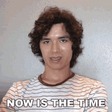 a young man with braces on his teeth is standing in front of a wall that says now is the time